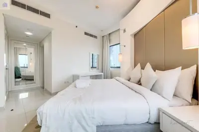 a white bedroom with a large white bed with white pillows at Luxury Downtown Dubai Stay Next to Mall of Dubai in Dubai