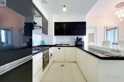 a kitchen with white cabinets and black counter tops at Luxury Downtown Dubai Stay Next to Mall of Dubai in Dubai