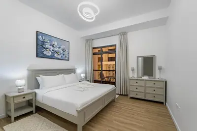 a white bedroom with a bed and a mirror at Elegant 2BR with Seaview in JBR l Walk to the Beach in Dubai