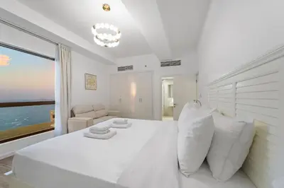 a white bedroom with a large bed and a window at Elegant 2BR with Seaview in JBR l Walk to the Beach in Dubai