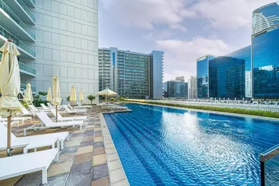 a swimming pool with chairs and umbrellas on a building at Exclusive 1-Bedroom Apartment with Breathtaking Burj Khalifa Views in the Heart of Dubai in Dubai
