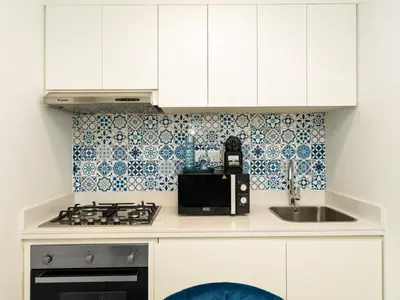 a kitchen with white cabinets and a sink and a microwave at Luxury Apartment with Balcony & Full Burj Khalifa View by Dejaview Stays in Dubai