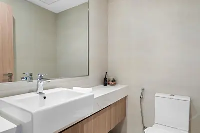 a bathroom with a sink and a toilet and a mirror at 1BR Azizi Riviera B7, Pool View in Dubai