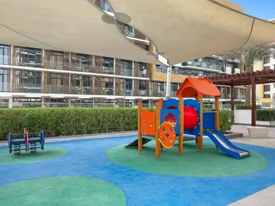a playground in front of a large building at 1BR Azizi Riviera B7, Pool View in Dubai