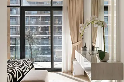 a living room with a table and a large window at 1BR Azizi Riviera B7, Pool View in Dubai