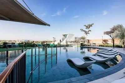 a swimming pool with four white chairs in the water at City Walk Green Planet View 1Br in Dubai