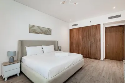 a bedroom with a white bed and a wooden door at City Walk Green Planet View 1Br in Dubai