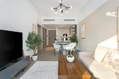 a living room with a couch and a table at Bespoke Holiday Homes - Stylish 1-BR Apartment in Oxford Terraces, JVC in Dubai