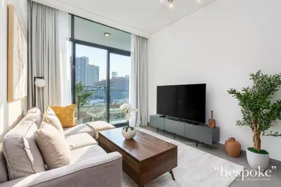 a living room with a couch and a tv at Bespoke Holiday Homes - Stylish 1-BR Apartment in Oxford Terraces, JVC in Dubai