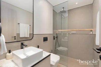 a white bathroom with a sink and a shower at Bespoke Holiday Homes - Stylish 1-BR Apartment in Oxford Terraces, JVC in Dubai
