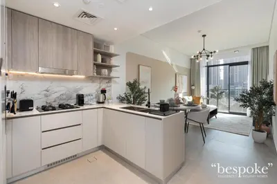a kitchen with white cabinets and a dining room at Bespoke Holiday Homes - Stylish 1-BR Apartment in Oxford Terraces, JVC in Dubai