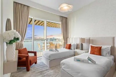 a hotel room with two beds and a balcony at Seaview Living 2 Bedroom - Grand Bleu by Elie Saab in Dubai