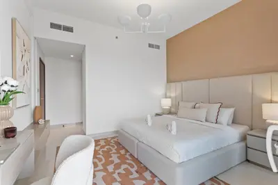 a bedroom with a large white bed and a desk at Seaview Living 2 Bedroom - Grand Bleu by Elie Saab in Dubai