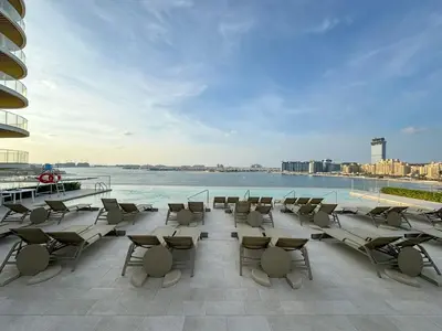 a patio with chairs and tables and the water at Seaview Living 2 Bedroom - Grand Bleu by Elie Saab in Dubai