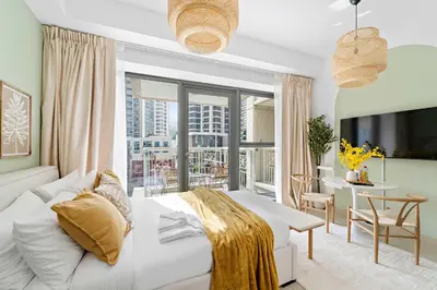 a bedroom with a white bed and a table and a balcony at Silkhaus Modern Studio with Burj Khalifa View in Dubai