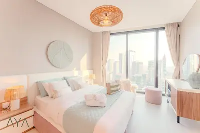 a bedroom with a bed and a desk and a window at Luxury Beachfront 1BR Jumeirah Gate Tower 1 By ĀYA Boutique in Dubai