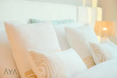 a white bed with four pillows on it at Luxury Beachfront 1BR Jumeirah Gate Tower 1 By ĀYA Boutique in Dubai