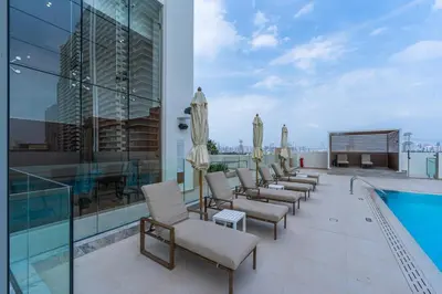 a balcony with chairs and a pool on a building at Smart living I High speed wi-fi I City view in Dubai