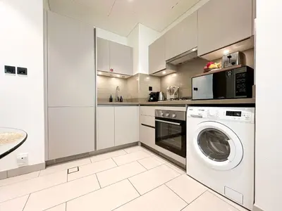 a kitchen with a washing machine and a microwave at Trophy - Elegant Cozy 1Bdr in Sobha Hartland in Dubai