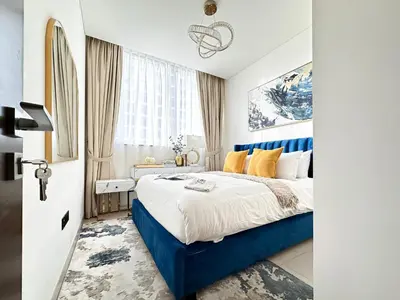 a bedroom with a blue and white bed and a window at Trophy - Elegant Cozy 1Bdr in Sobha Hartland in Dubai