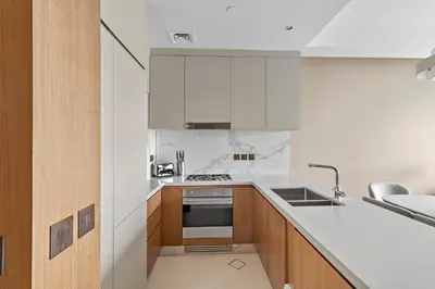 a kitchen with white appliances and wooden cabinets at 2BR Address Opera, Full Burj Khalifa View in Dubai