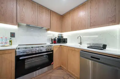 a kitchen with wooden cabinets and a stainless steel oven at Cosy Palm Jumeirah 1 Bedroom - Perfect Location in Dubai