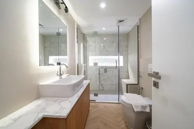 a white bathroom with a sink and a shower at Cosy Palm Jumeirah 1 Bedroom - Perfect Location in Dubai