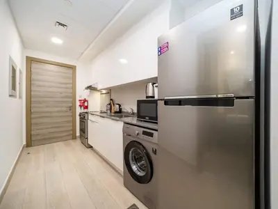 a kitchen with a stainless steel refrigerator and a dishwasher at Stylish Studio Living in the Heart of JVC in Dubai