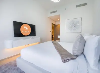 a bedroom with a white bed and a flat screen tv at EasyGo-Core Luxury 2BDR in Grande Signature Res panoramic view in Dubai