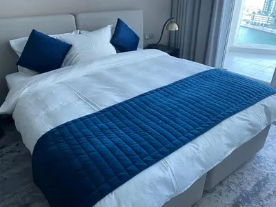 a bed with blue and white sheets and a window at Luxurious studio in Damac maison prive by Phineek vacation home in Dubai