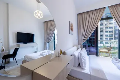 a hotel room with two beds and a desk at Elite LUX Holiday Homes - Upscale Studio in Azizi Riviera Prime Location Dubai in Dubai