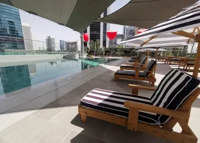 a row of lounge chairs sitting next to a swimming pool at Stylish Studio, MAG 318 in Dubai
