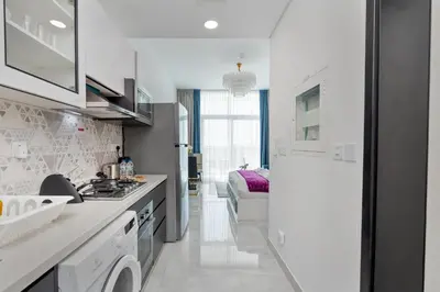 a white kitchen with a sink and a stove at Vacay Lettings - Pearlz By Danube -Studio-Al Furjan-Near Metro in Dubai