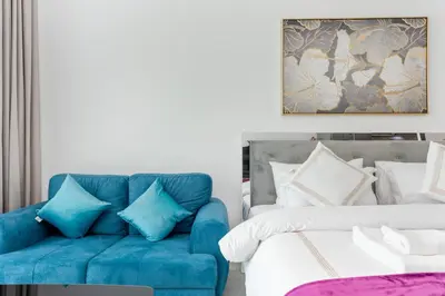 a bedroom with a blue couch next to a bed at Vacay Lettings - Pearlz By Danube -Studio-Al Furjan-Near Metro in Dubai