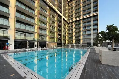 a large swimming pool in front of a building at Cozy 1BR with balcony in Binghatti Emerald in Dubai