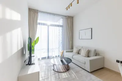 a white living room with a couch and a table at Cozy 1BR with balcony in Binghatti Emerald in Dubai