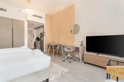 a hotel room with a bed and a flat screen tv at Vacay Lettings - Spacious Studio Apartment - Production City in Dubai