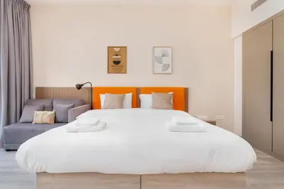 a bedroom with a large white bed and a blue couch at Vacay Lettings - Spacious Studio Apartment - Production City in Dubai