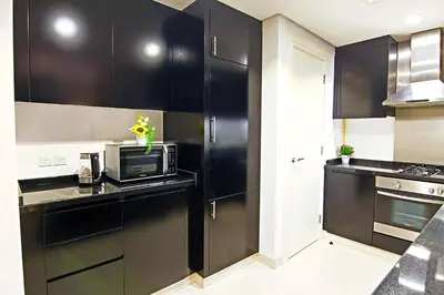 a kitchen with black cabinets and a microwave at Luxurious 1bhk in Cour Jardin in Dubai