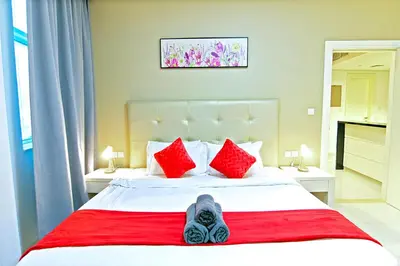 a person laying on a bed with red pillows at Luxurious 1bhk in Cour Jardin in Dubai