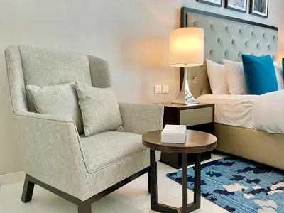 a living room with a chair and a bed at Vacay Lettings - Modern Studio Near to Expo City in Dubai