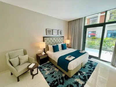 a bedroom with a bed and a chair and a window at Vacay Lettings - Modern Studio Near to Expo City in Dubai