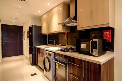 a kitchen with wooden cabinets and a washer and dryer at Luxurious Elite Studio-DownTown in Dubai