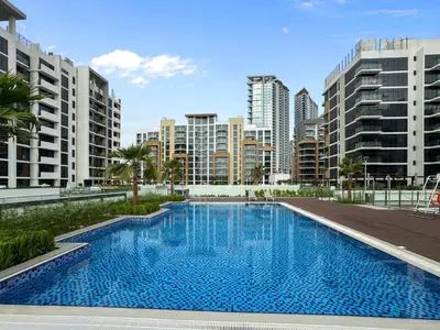 a large swimming pool in a city with tall buildings at Sleek Studio Apartment in Azizi Riviera in Dubai