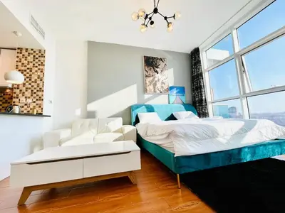 a bedroom with a bed and two white chairs at Studio apartment in jumeriah village triangle district 2 in Dubai