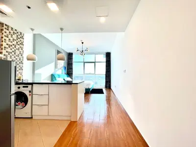 a kitchen with white walls and a wooden floor at Studio apartment in jumeriah village triangle district 2 in Dubai