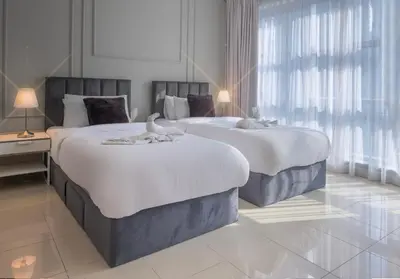 two beds in a room with two tables and a window at Stylish 2 Bedroom Opera View in Downtown Dubai SP2013 in Dubai
