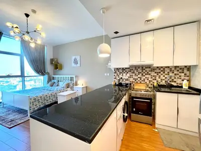 a kitchen with a counter top and a living room at Studio apartment in jumeriah village triangle district 2 in Dubai