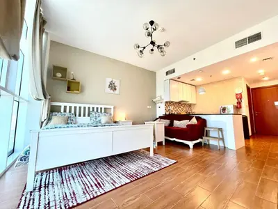 a living room with a white bed and a red couch at Studio apartment in jumeriah village triangle district 2 in Dubai