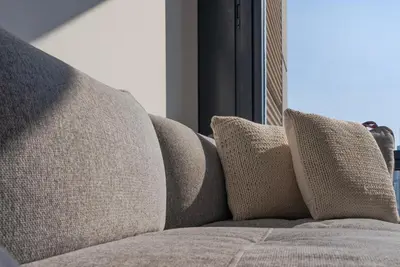 a couch with three pillows on it next to a window at Stunning Burj Khalifa & Downtown Views - Elegant 1BR in The Iconic Index Tower in Dubai